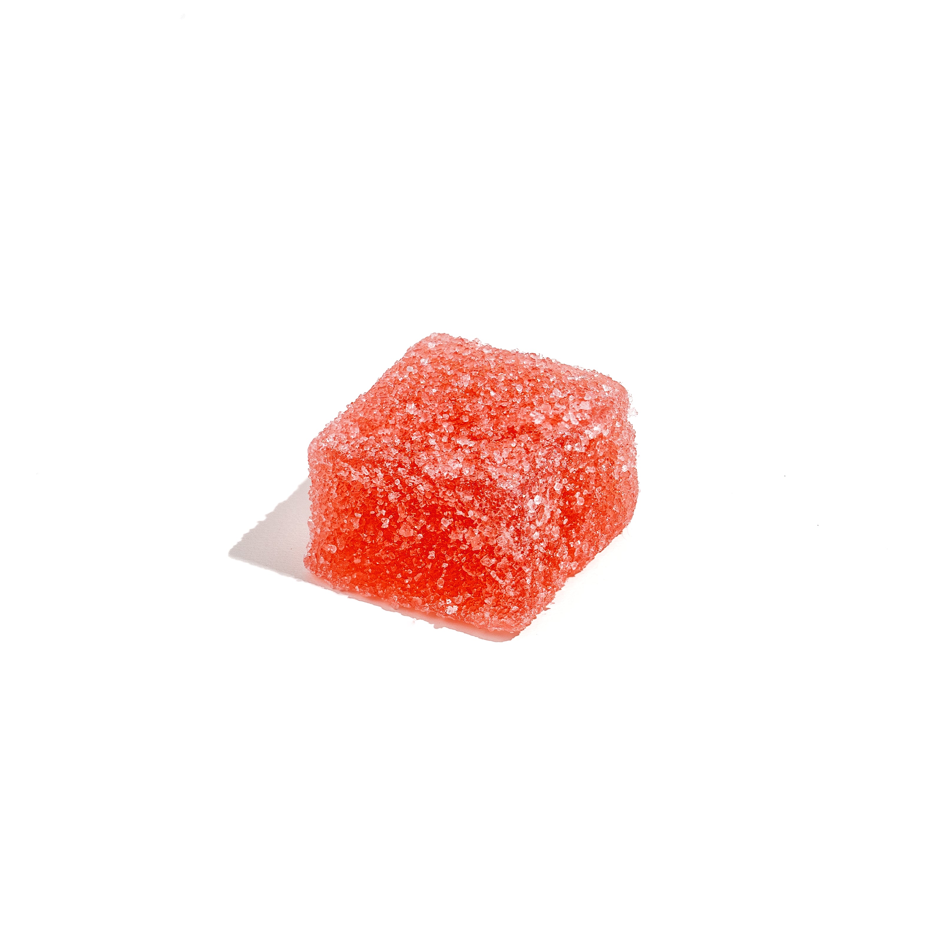 Close-up of a red, sugar-coated CBD gummy cube on a white background, showcasing sample size for wellness discovery from Honey Bloom.